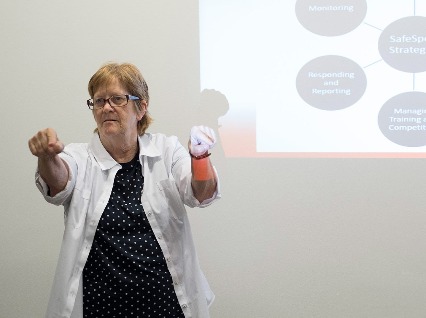 Christine Buchholz signs 'can' with her presentation in the background